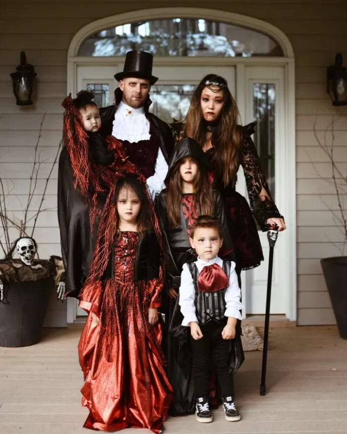Family wearing gothic vampire costumes in deep red and black.